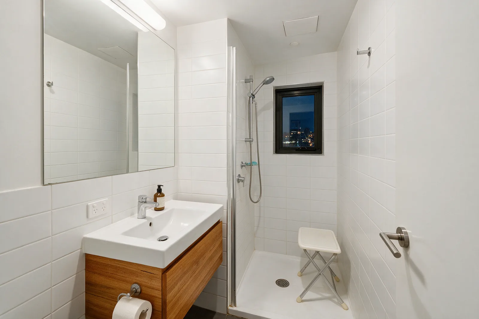 Compact Braddon apartment bathroom with a foldable shower stool