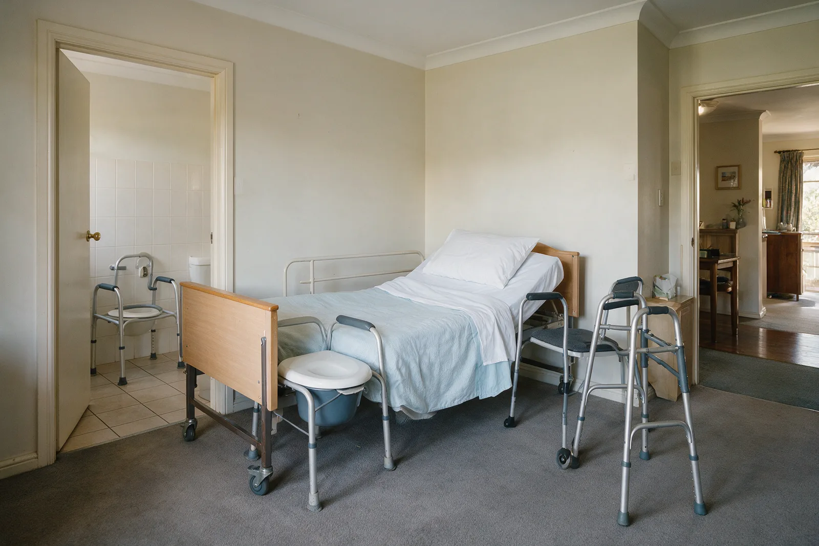 Bedroom set up for hospital discharge with a commode chair and walking frame