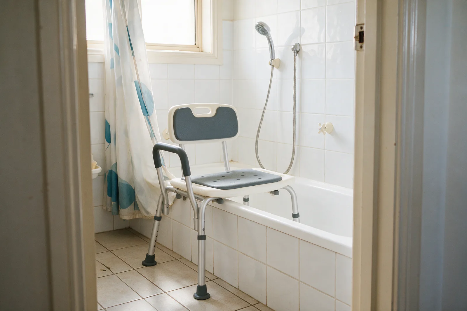 Bath transfer bench straddling the edge of a bathtub with a shower curtain
