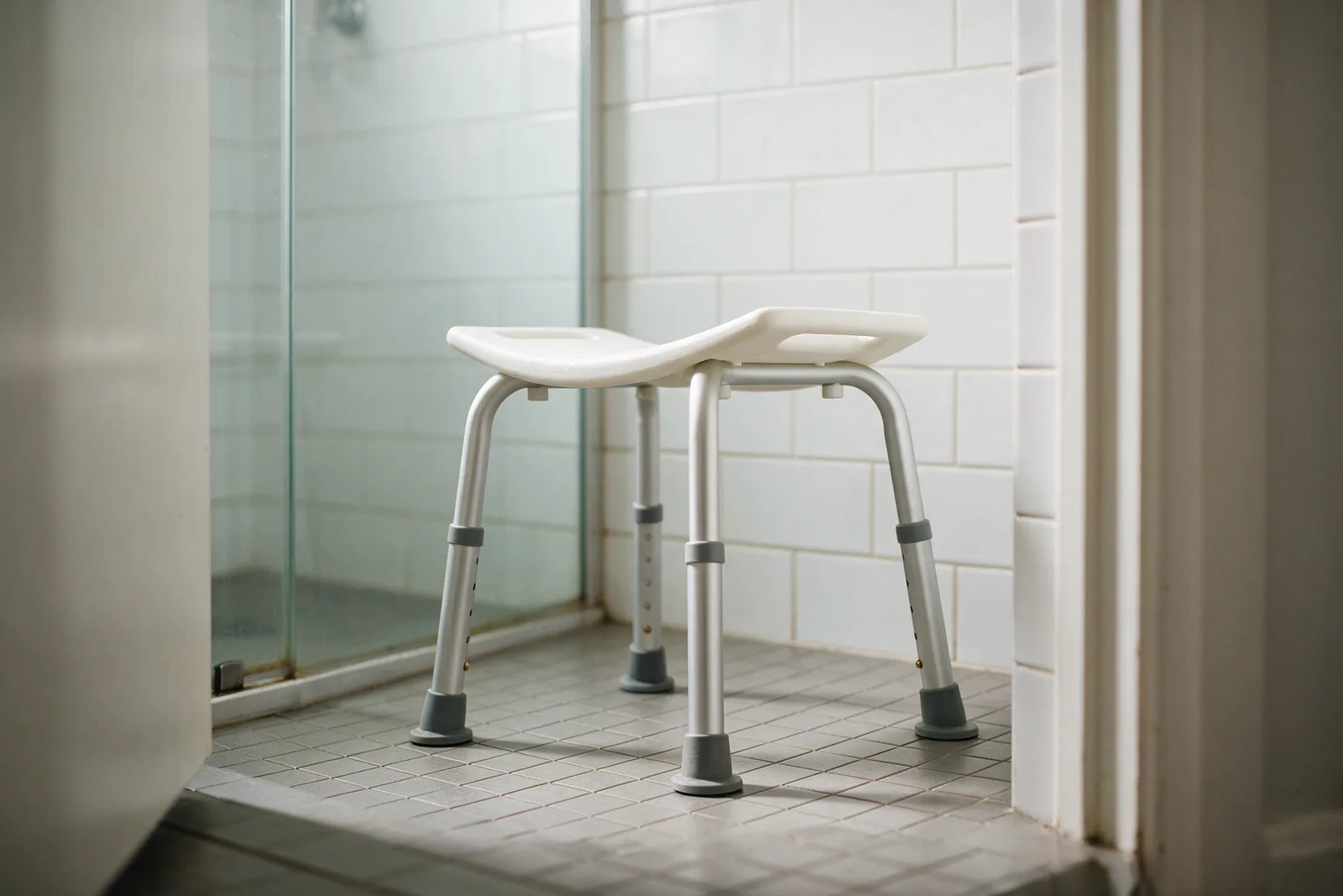 Height-adjustable shower stool in a compact apartment shower recess
